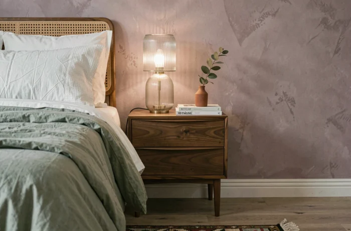 Coin chambre moderne et cosy avec table de chevet en noyer, literie en coton sage et mur en badigeon prune