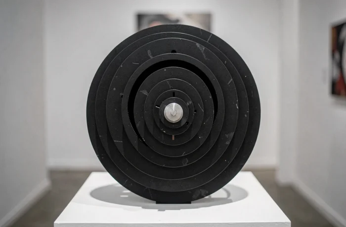 Sculpture cinétique en disques acryliques noirs créant une illusion d'optique de mouvement dans une galerie d'art